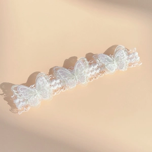 Detailed close-up of white lace baby headband with three delicate butterfly embroidery