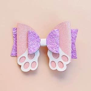Close-up of glittery pink and purple bow hair clip with white cat paw cutouts