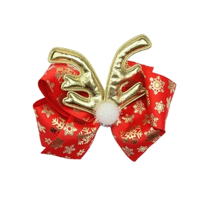Detail of red Christmas bow hair clip with gold snowflake prints and reindeer antlers