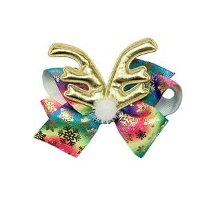 Detail of Christmas bow hair clip with rainbow ribbon, white pompom and gold reindeer antlers