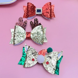 Close-up of three Christmas glitter hair clips with reindeer antlers and pom-pom bows