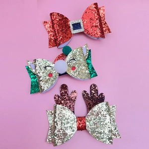 Detailed view of three festive Christmas glitter hair clips with reindeer and bows