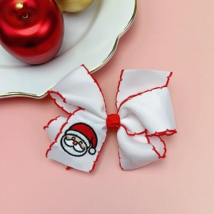 Detail of Christmas bow hair clip with Santa embroidery and red stitched edges