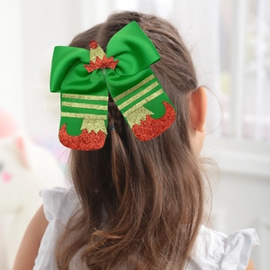 Detail of Christmas elf bow hair clip with green ribbons and glittery red boots