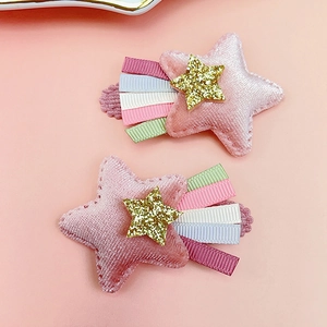 Détail de barrettes étoile rose floqué avec paillettes dorées et queue ruban arc-en-ciel