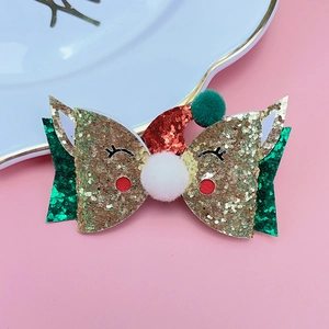 Detail of Christmas reindeer hair clip with sequins, pom-poms and bow on pink background