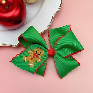 Detail of Christmas bow hair clip with gingerbread man embroidery on green ribbed ribbon