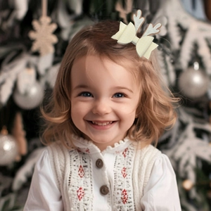 Primer plano de niña con clip navideño de cuernos de reno y lazo en ambiente festivo