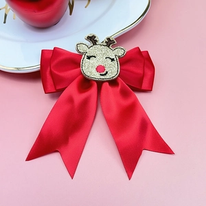 Detail of red satin bow hair clip featuring a festive reindeer motif for Christmas