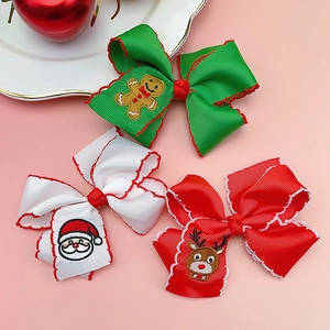 Detail view of three Christmas hair bows with embroidery of Santa, reindeer, and gingerbread