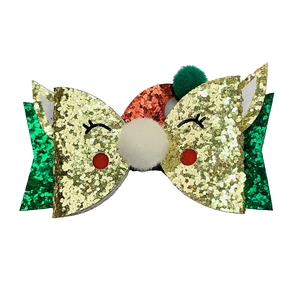 Detail of Christmas glitter bow hair clip with white pompom and red sequin hat design