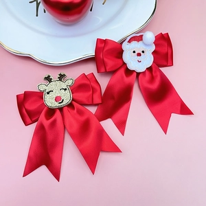Close-up of red satin Christmas hair bows with embroidered Santa and glitter reindeer motifs