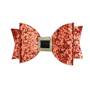 Close-up of glittery red Christmas bow hair clip with Santa Claus belt buckle detail