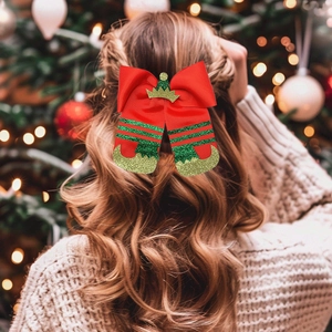 Close-up of red and green Christmas bow hair clip with elf boots on wavy blonde hair