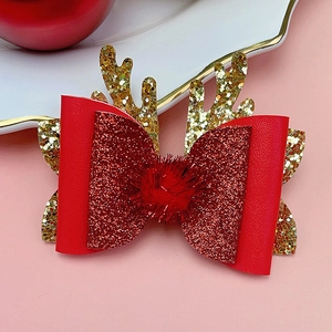 Detail of Christmas reindeer antler hair clip with red bow, glitter, and pom pom