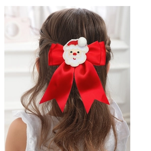 Detail view of a large red satin ribbon bow hair clip with Santa Claus embroidery on hair
