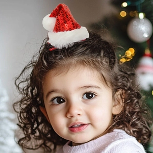 Close-up of a child wearing a sparkly red sequin Christmas hat hair clip with white fur
