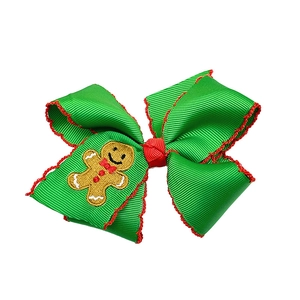 Detail of Christmas green grosgrain bow clip with red ruffle edge and gingerbread man embroidery