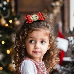 Close-up of a red sequin bow hair clip with a smiling face on a girl for Christmas