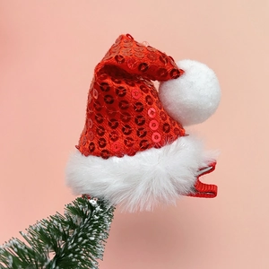 Close-up of red sequined Christmas hat hair clip with white plush ball on tree branch