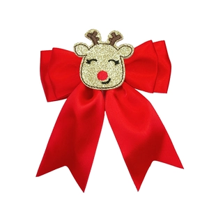 Detail of red Christmas hair bow with golden glitter reindeer and red nose accent