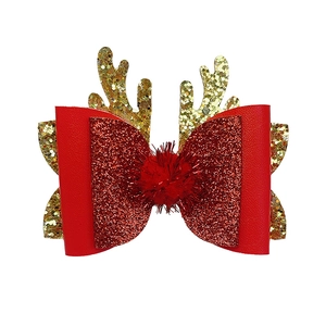 Close-up of Christmas hair clip with red glitter bow, plush ball, and golden reindeer antlers