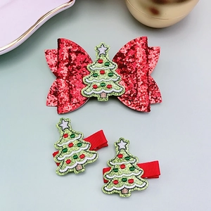 Detail of Christmas hair clip set featuring red sequin bow with green tree embroidery