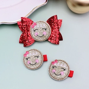 Detail view of red glitter bow and sequin smiley hair clips for children's holiday styling