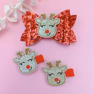 Detailed view of festive Christmas hair clips featuring a red bow and reindeer with sequins