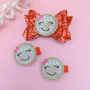 Detail view of 3-piece Christmas hair clips set with red sequin bow and cute smiley faces