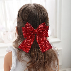 Dettaglio di un grande fiocco di paillettes rosse con nastri sui capelli di una ragazza