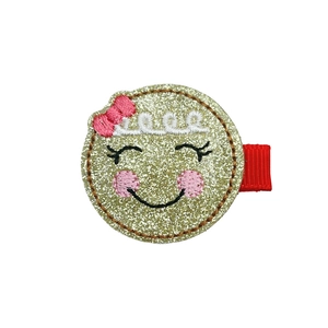 Detail of glitter gold gingerbread face hair clip with embroidery and red bow