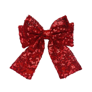 Dettaglio del fermaglio a fiocco con paillettes rosse con trama lucida e brillante