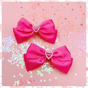 Detail van twee roze satijnen haarstrikken met zilveren hartvormige strass gespen
