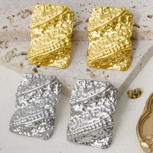 Detail of gold and silver rectangular earrings with irregular hammered lava texture