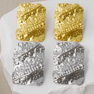 Macro detail of geometric 304 stainless steel earrings with irregular molten texture finish