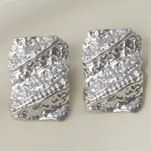 Detail shot of rectangular silver stud earrings with hammered lava texture and ridges