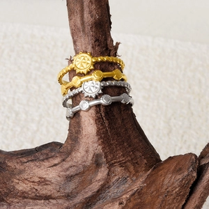 Detail of stacked sunburst rings and beaded bands on a dry wooden branch