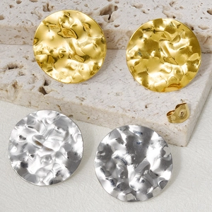 Macro detail of textured hammered oval earrings in gold and silver finish on stone