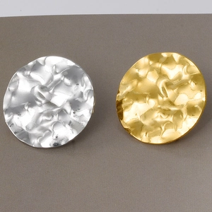 Detailed macro view of gold and silver hammered oval stud earrings with textured finish