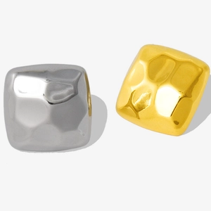 Detail of square gold and silver earrings with hand-hammered texture and metallic luster