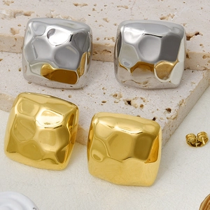 Detail of square hammered metal stud earrings in gold and silver finish with textured surface