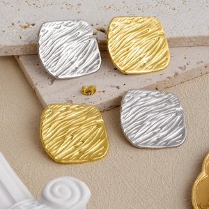 Detailed macro view of 18k gold and silver earrings with textured hammered finish on stone