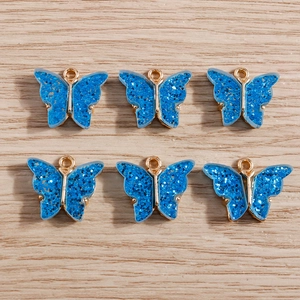 Detailed view of six blue glitter acrylic butterfly charms with gold alloy loops