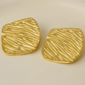 Macro shot of gold-plated stainless steel earrings with textured diamond-pattern surface