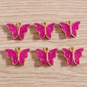Set of six pink acrylic butterfly pendants with gold metal frames and sparkling sequins