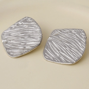 Detailed close-up of silver earrings with irregular square shape and water ripple texture