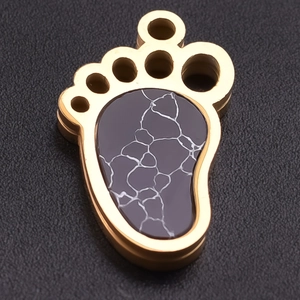 Macro shot of gold stainless steel paw pendant featuring marble textured inlay detail