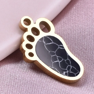 Macro detail of paw print pendant featuring gold metal border and black marble inlay pattern