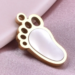 Detailed macro view of golden stainless steel paw pendant with white inlay on purple fabric